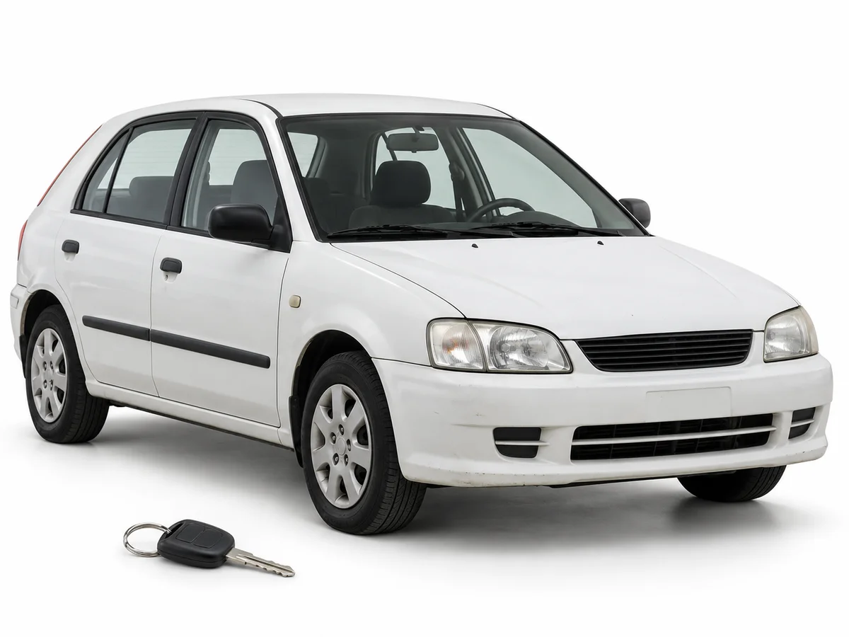 An older white hatchback with its key in the foreground